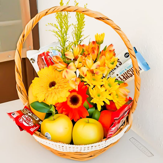 Canasta floral dorada con frutas y chocolates.